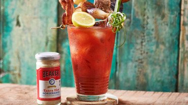 Iced bloody mary topped with lemon, bacon, steak, and onions, plus Beaver Brand Extra Hot Horseradish