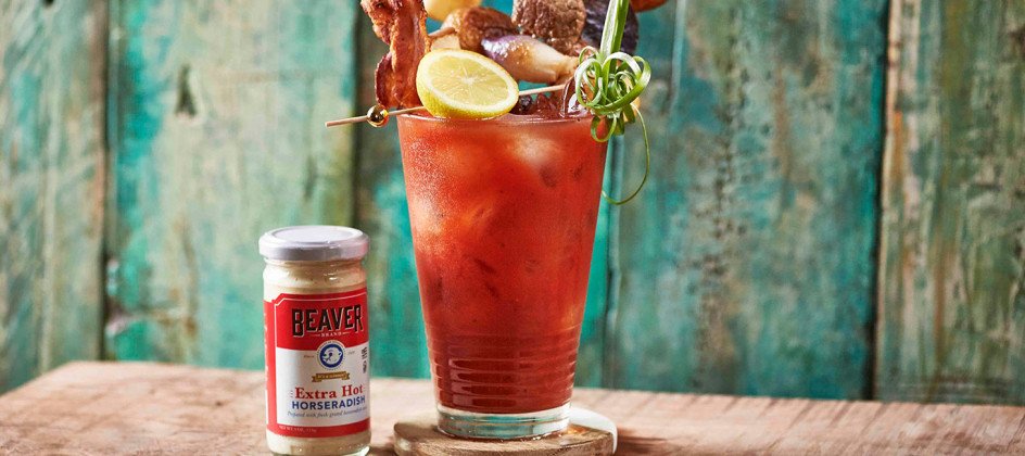 Iced bloody mary topped with lemon, bacon, steak, and onions, plus Beaver Brand Extra Hot Horseradish